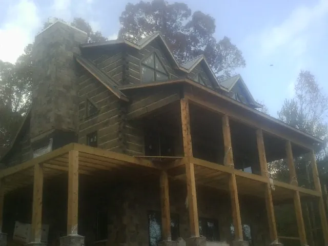 Stone chimney and dormers on a large log home with a timber porch in Fruitland